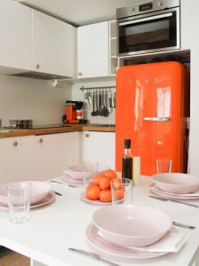 a kitchen with white cabinets and an orange refrigerator at La Petite bohéme with free parking in Stockholm