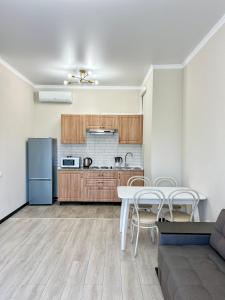 a kitchen and dining room with a table and a refrigerator at Апартаменты в ЖК LEGENDA, Алматы (Apartment in LEGENDA Residence) in Almaty
