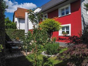 a red house with a table in a garden at Ferienhaus in den Auen in Markdorf