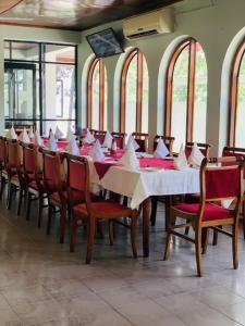 a dining room with a long table with red chairs at Lake Side Tourist Inn in Tissamaharama