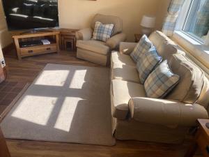 sala de estar con sofá y silla en Houghton Park Holiday Cottage en Newcastleton