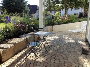 een tafel en stoelen op een patio met bloemen bij Ferienwohnung Huber in Markdorf