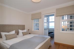 ein weißes Schlafzimmer mit einem großen Bett und zwei Fenstern in der Unterkunft Seehof Seehof 24 in Bansin