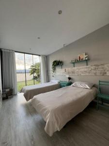 1 dormitorio con 2 camas y ventana grande en Casa Calima en Esteiro