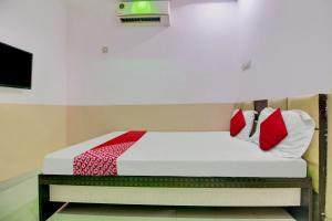 Una cama con almohadas rojas y blancas. en Super OYO Flagship Hotel Vinit Lodging en Nagpur