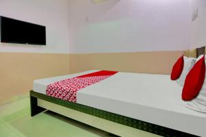 una camera con letto con lenzuola rosse e TV a schermo piatto di OYO Flagship Hotel Vinit Lodging a Nagpur
