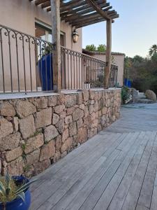 a patio with a stone wall and a wooden deck at Mer & Maquis in Bonifacio