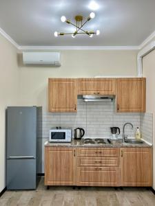 a kitchen with wooden cabinets and a refrigerator at Апартаменты в ЖК LEGENDA, Алматы (Apartment in LEGENDA Residence) in Almaty