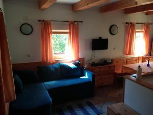 a living room with a blue couch and two windows at Apartma Brin Bovec in Bovec
