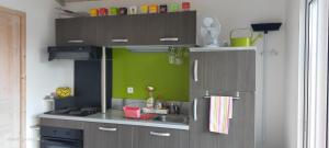 una cocina con armarios marrones y una pared verde en Gîte climatisé L'OISELLERIE en Castelnou