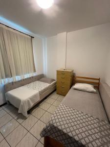 um quarto com 2 camas e uma cómoda e uma janela em Apto 2 dormitórios em Balneário Camboriú no Balneário Camboriú