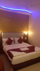HOTEL COSTA DEL في مومباي: غرفة نوم مع سرير كبير مع ضوء أرجواني