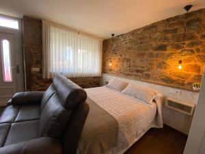 a bedroom with a couch and a stone wall at Apartamentos Currás en Touriñán in Touriñán