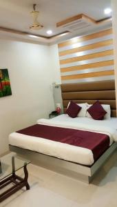 孟買的住宿－HoteL Namaste London Terminal-2，一间卧室配有一张大床和木制床头板