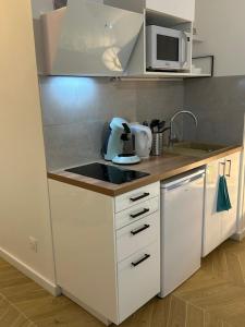 a kitchen with white cabinets and a microwave at Studio L'échappée avec lit double et parking sous-sol privatif in Chartres