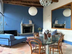 een eetkamer met een glazen tafel en een blauwe muur bij Casa Stella a due passi da Orta in Ameno