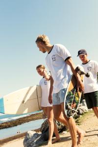 un gruppo di persone che camminano sulla spiaggia con uno skateboard di Aparra Surfcamp Capbreton a Capbreton