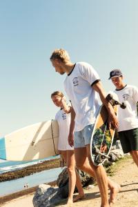 a group of people walking on the beach with a skateboard at Aparra Surfcamp Auberge Capbreton in Capbreton