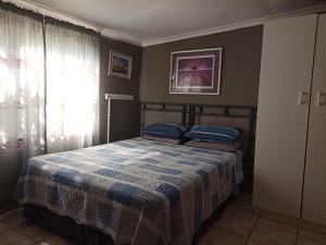 a bedroom with a bed with a blue and white blanket at Villa Luca Guesthouse & Chalets in Swartruggens