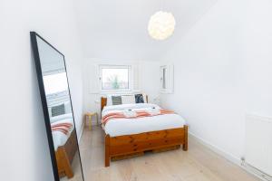 um quarto branco com uma cama e um espelho em Stylish 1BR apt, 7min Archway Tube & Holloway Rd em Londres