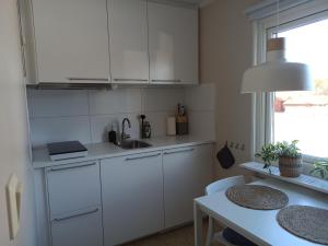 a white kitchen with a sink and a table at SunnemosLantLiv in Sunnemo