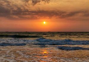 a sunset on the beach with the ocean at Baga Keys by RJ14 in Old Goa