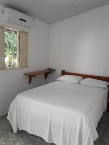a white bed in a white bedroom with a window at Pouso da Lapa in Pirenópolis