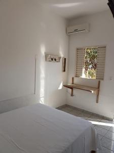 a white bedroom with a bed and a window at Pouso da Lapa in Pirenópolis
