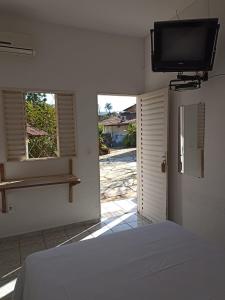 um quarto com uma cama e uma televisão na parede em Pouso da Lapa em Pirenópolis