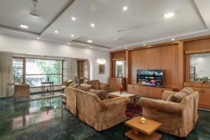 een woonkamer met banken en een flatscreen-tv bij Woodstone Manor by JadeCaps Penthouse Indiranagar in Bangalore