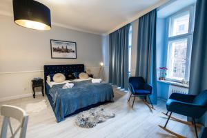 um quarto azul com uma cama e 2 cadeiras em Apartament Hampton em Toruń