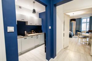 uma cozinha com armários brancos e uma parede azul em Apartament Hampton em Toruń