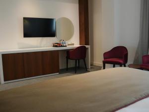 a hotel room with a tv and two chairs at Ramada Hotel & Suites by Wyndham Erbil 32 Park in Erbil