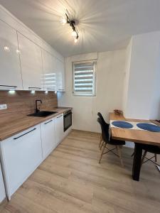 a kitchen with white cabinets and a table and a sink at Apartman Mona in Teslić