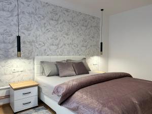 een slaapkamer met een bed met een bloemaccentmuur bij Apartman Mona in Teslić