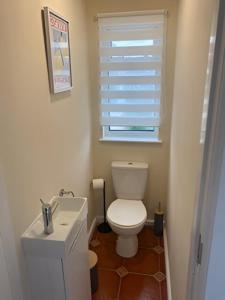 a bathroom with a toilet and a sink and a window at Bungalow Three Bedroom The Park Onchan Isle of Man in Onchan