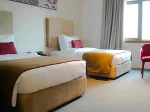 um quarto de hotel com duas camas e uma cadeira em Ramada Hotel & Suites by Wyndham Erbil 32 Park em Arbil