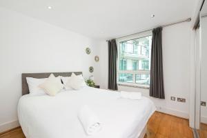 - une chambre blanche avec un grand lit blanc et une fenêtre dans l'établissement Compact 2 Bed Good Transport Links, à Londres