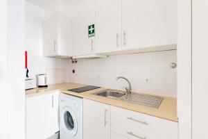 eine weiße Küche mit einer Spüle und einem Geschirrspüler in der Unterkunft Alfama Studios in Lissabon