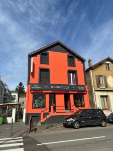 an orange building with a car parked in front of it at O Barcaiolo in Conflans-Sainte-Honorine