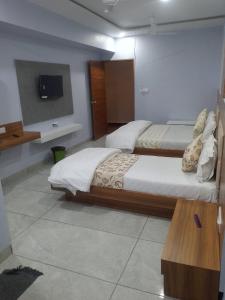 a bedroom with two beds and a tv on the wall at Hotel Red Blue,Ahmedabad in Naroda