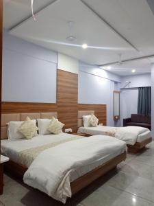 Hotel Red Blue,Ahmedabad في Naroda: سريرين في غرفة بجدران بيضاء