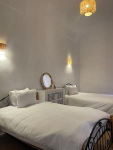 1 dormitorio con 2 camas y espejo en la pared en Éden Rouge Marrakech en Marrakech