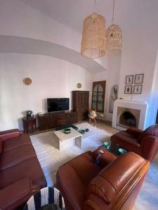 sala de estar con muebles de cuero y chimenea en Éden Rouge Marrakech en Marrakech