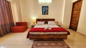 um quarto com uma cama grande e uma cadeira vermelha em Yogvan Luxury 1BHK Apartments Tapovan Rishikesh em Rishikesh