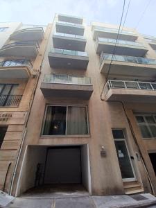 Sliema Apartment close to BEACH في سليمة: مبنى طويل وبه شرفات على جانبه