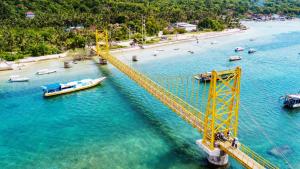 a yellow bridge over a body of water with a boat at Best Choice Nusa Lembongan in Nusa Lembongan