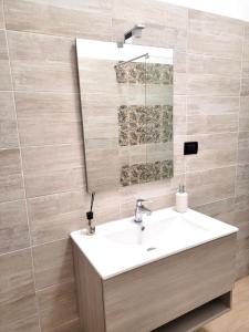 uma casa de banho com um lavatório branco e um espelho. em Messina’s apartment em Messina
