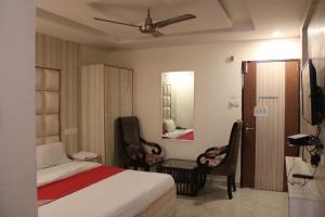 ZirakpurにあるHOTEL FIRSTのベッドルーム1室(ベッド1台、椅子2脚、鏡付)
