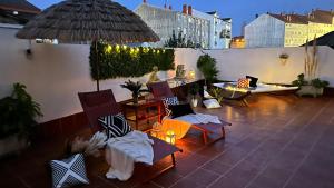 a patio with chairs and tables and an umbrella at Maison Terrasse Doña Irma in Cambados